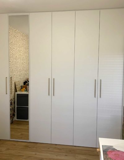 Vue générale d'un dressing blanc et bois avec miroir, penderie et rangements. Sur mesure.