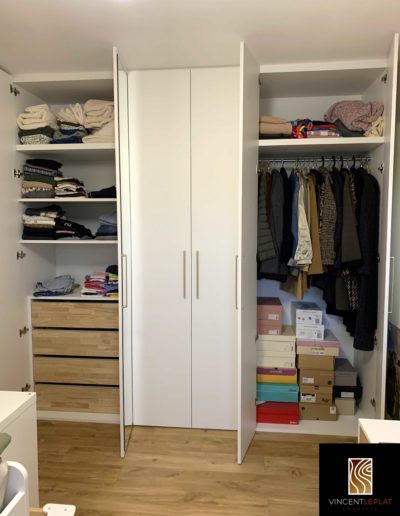 Vue intérieure d'un dressing bois et blanc.. Meuble sur mesure. Avec tiroirs et miroir.